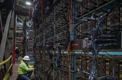 A modern mining farm in a large warehouse with rows of ASICs.